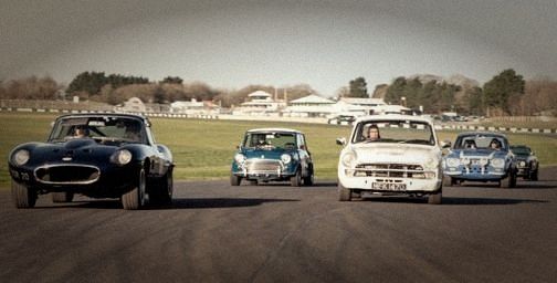 An E-type, Mini, Lotus Cortina and Escort side by side on a circuit