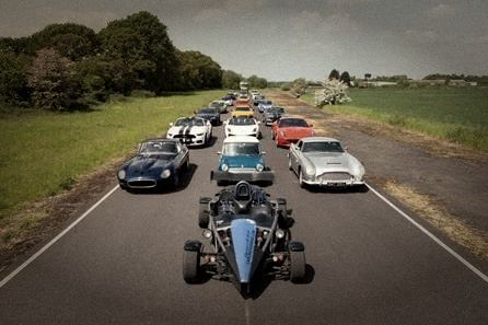 A convoy of supercars and classics on a quiet country road